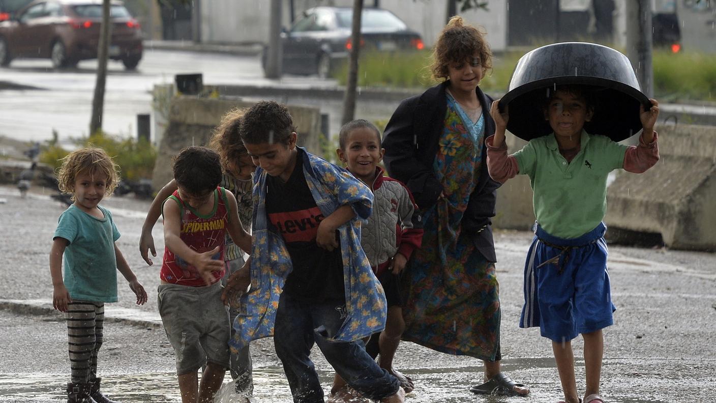 Internally displaced Lebanese children play in the rain water outside their tents during a rainy day at Martyrs Square in Beirut, Lebanon, 02 November 2024. T