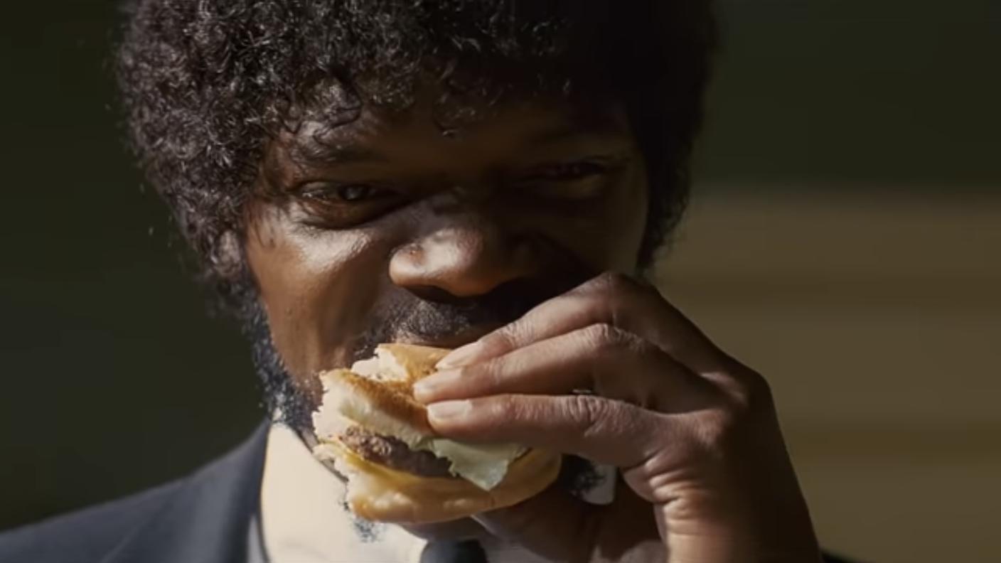 Samuel L. Kackson in una scena di Pulp Fiction (1994) mentre “ruba” l’iconico hamburger Royale with cheese del Big Kahuna. Il cibo, in questa scena - come in tante altre occasioni nei film di Tarantino – vuole simboleggiare la supremazia, il potere di un personaggio rispetto a un altro, in modo irriverente e senza filtri. 