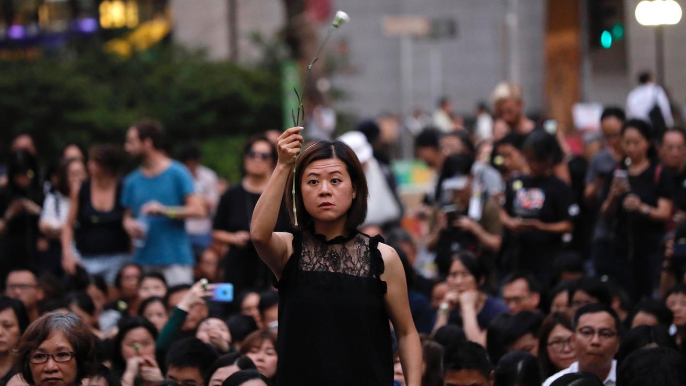 Una donna tiene un fiore mentre manifesta insieme ad altre centinaia di mamme 