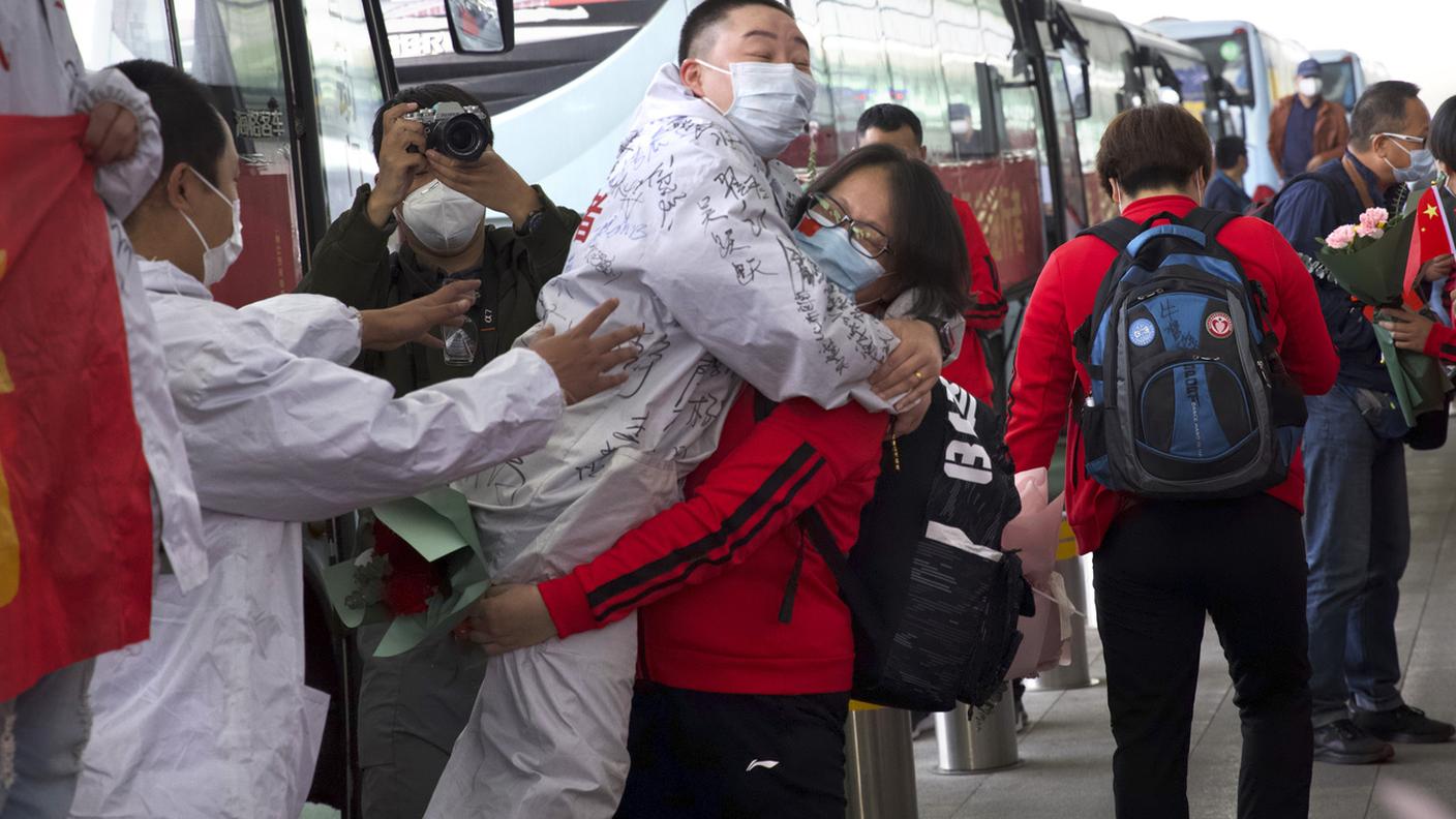 Due operatori della sanità si abbracciano all'aeroporto di Wuhan