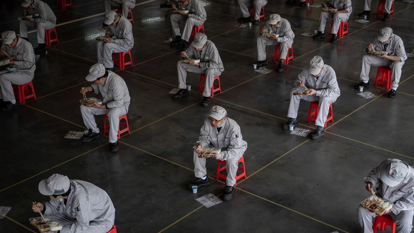 La pausa pranzo dei lavoratori della Honda a Wuhan, in uno scatto del 23 marzo 2020