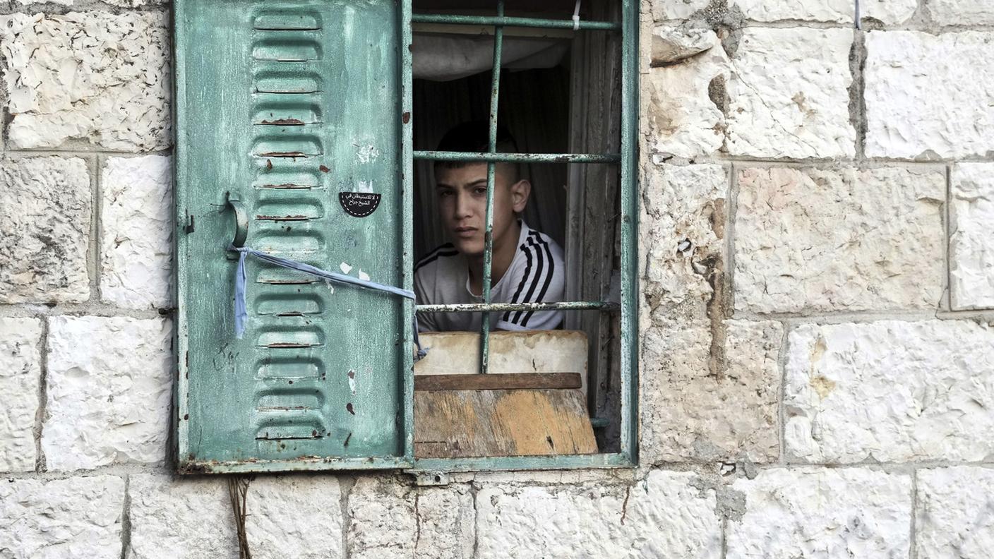 Un ragazzo palestinese affacciato alla finestra a Gerusallemme Est