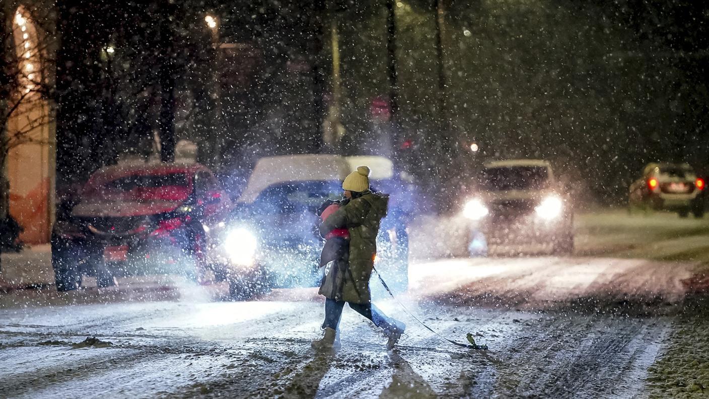 Una ragazza porta in braccio il suo cane durante una tempesta di neve in Pennsylvania