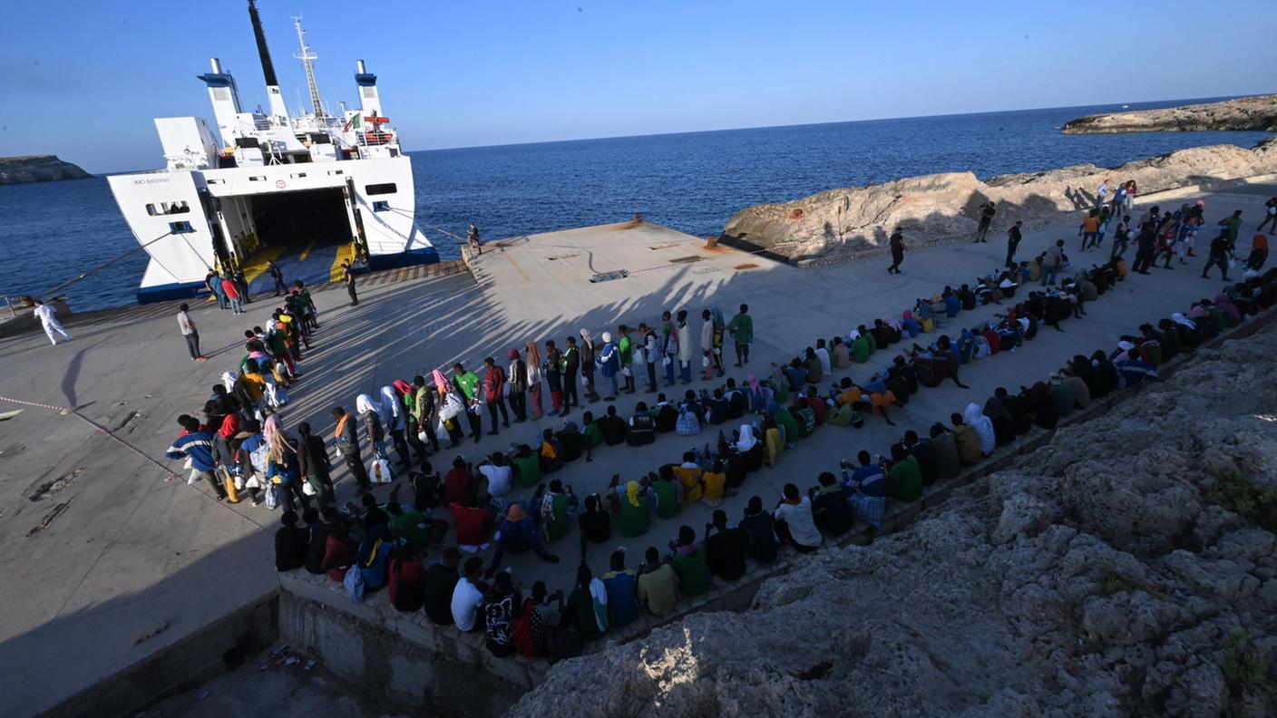 Migranti in attesa di essere trasferiti sulla terraferma a Cala Pisana, sull'isola siciliana di Lampedusa