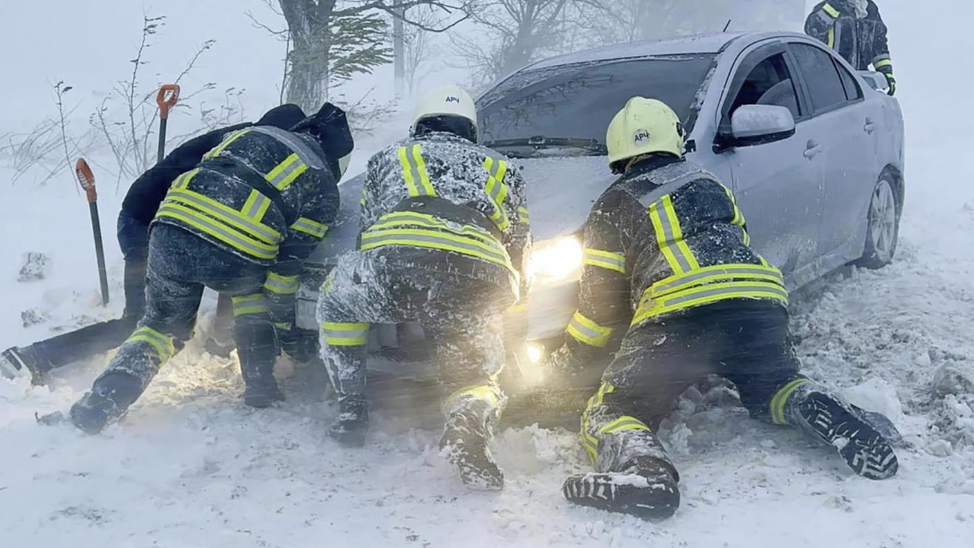 Soccorritori provano a liberare un'auto imprigionata dalla neve vicino a Odessa
