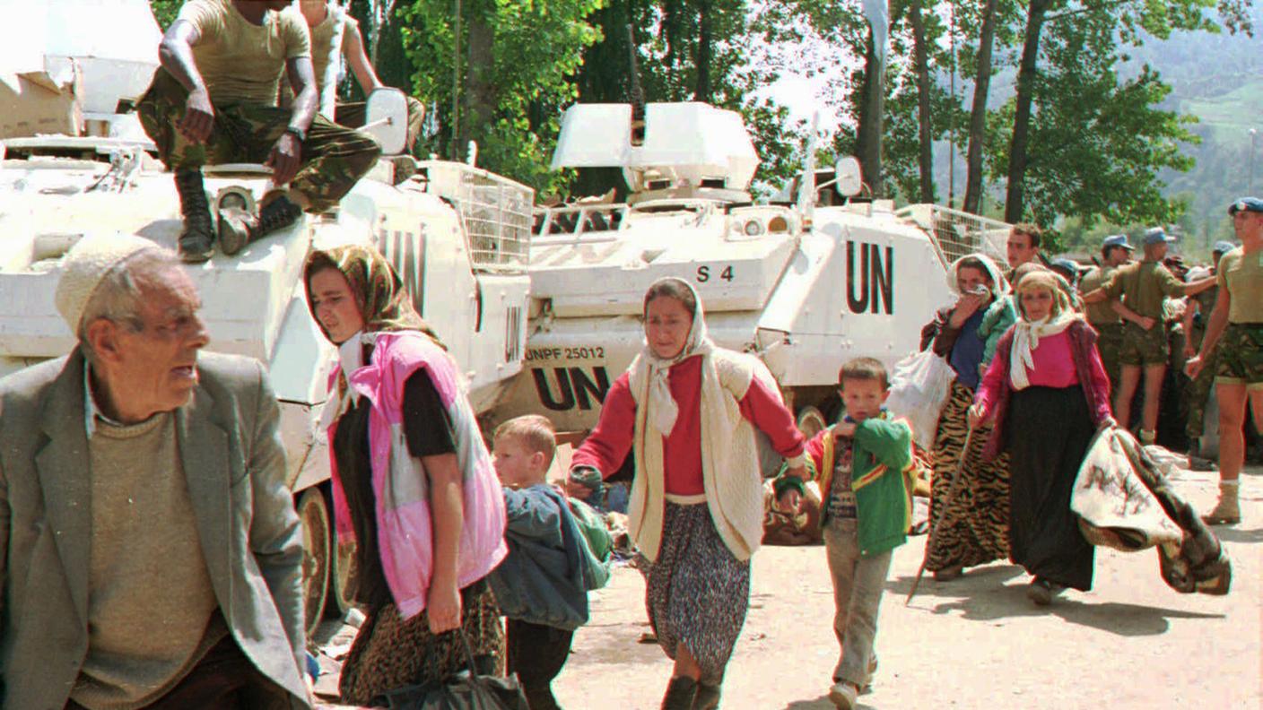 Rifugiati musulmani da Srebrenica, nella Bosnia orientale, passano accanto ai mezzi corazzati delle Nazioni Unite nel villaggio di Potocari, appena a nord di Srebrenica, in questa fotografia del 13 luglio 1995.