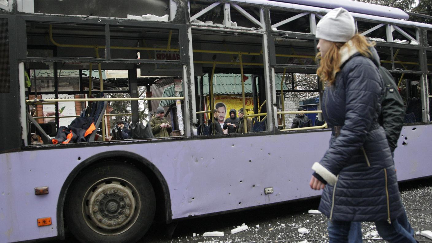 Una ragazza passeggia a fianco del bus sventrato da un colpo di mortaio Reuters.jpg
