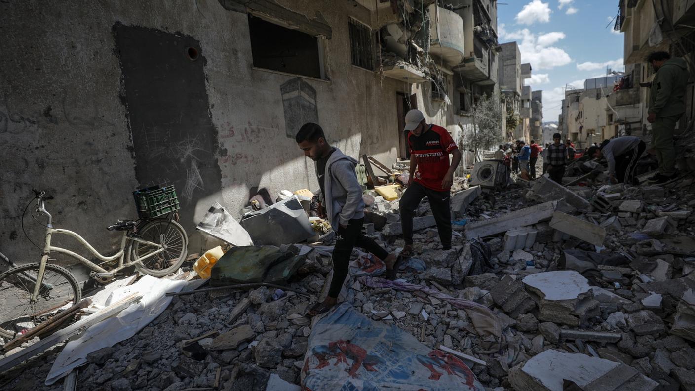 Palestinesi camminano tra le macerie
