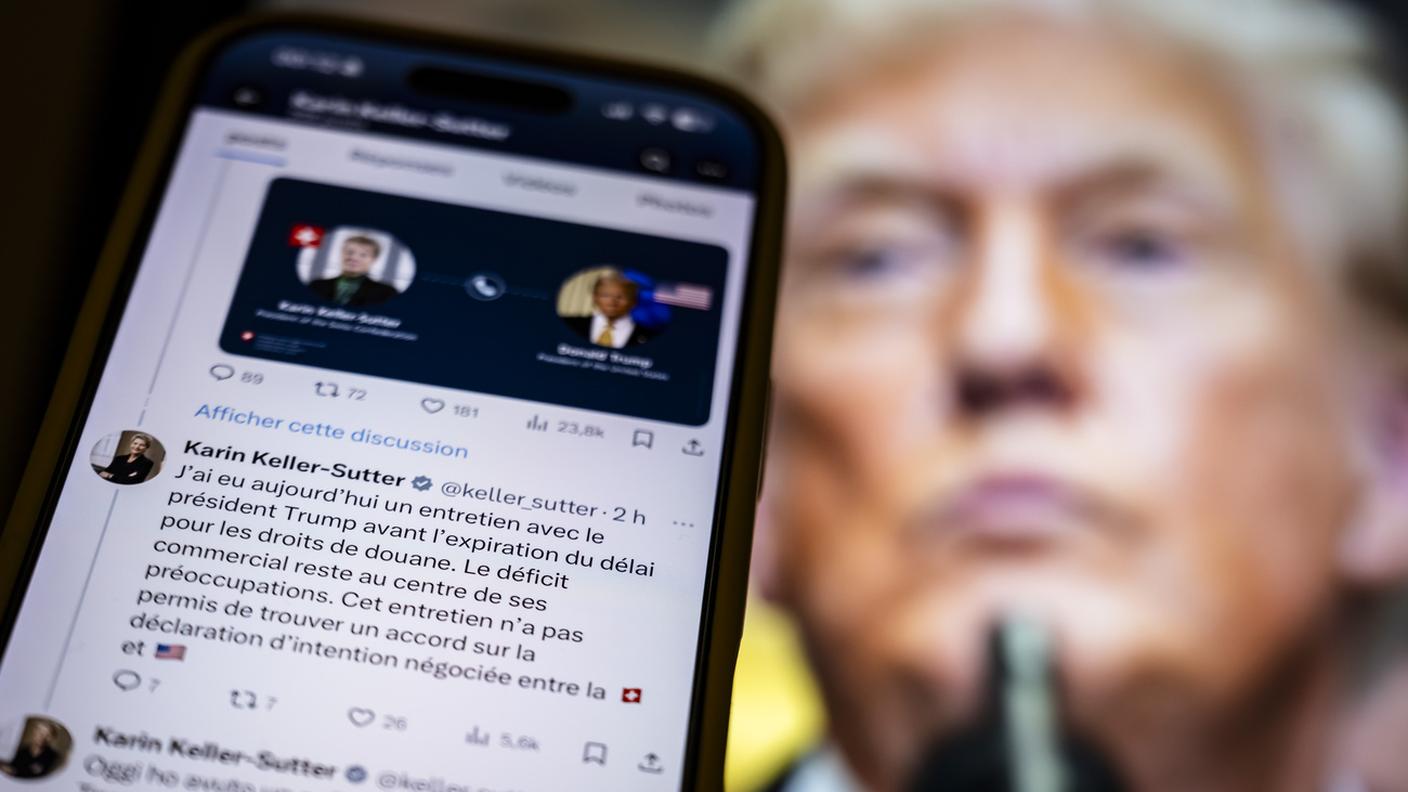 Il post su X di Karin Keller-Sutter sui dazi doganali visibile su uno smartphone davanti a una foto di Donald Trump KEY.jpg
