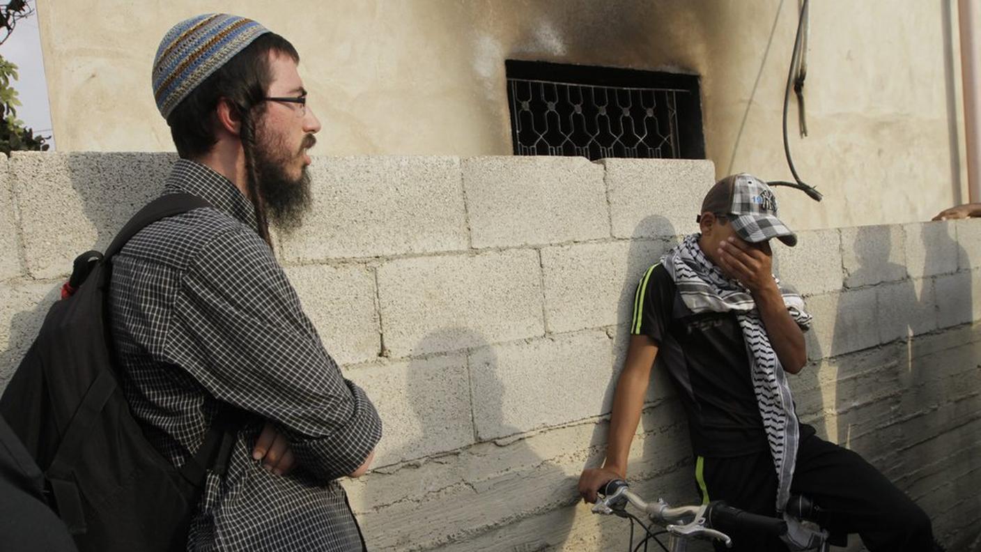 Un pacifista israeliano (a sinistra) di fronte alla casa della strage di Duma 