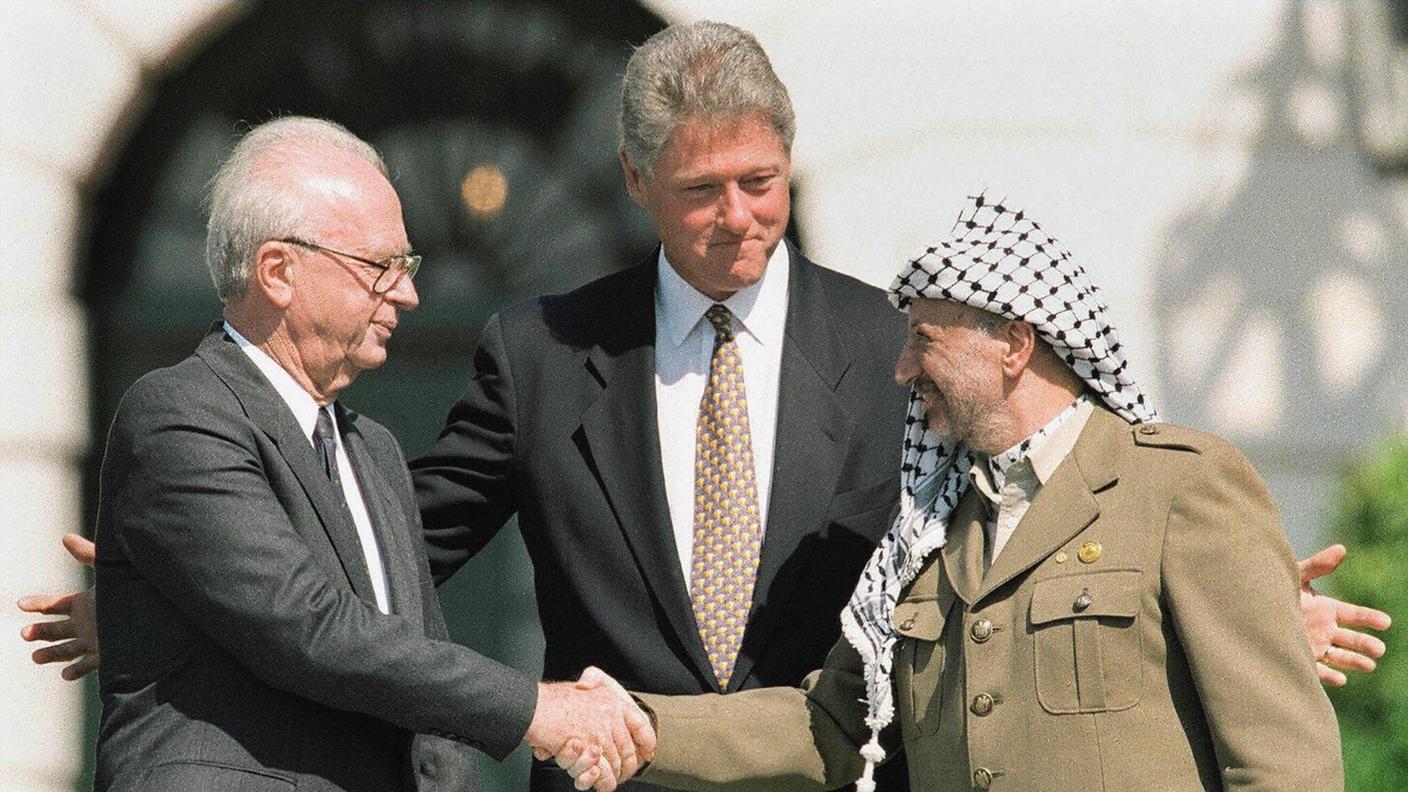 Il premier israeliano Yitzhak Rabin stringe la mano al leader palestinese Yasser Arafat davanti al presidente USA Bill Clinton a Washington (13 settembre 1993)