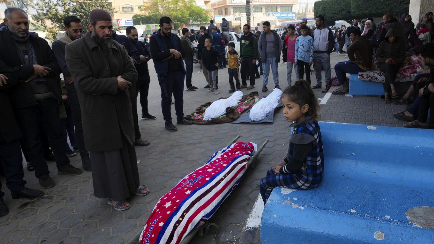 Palestinesi pregano per i parenti uccisi nei bombardamenti israeliani sulla Striscia di Gaza, davanti all'obitorio dell'ospedale di Deir al Balah (18 dicembre 2023)