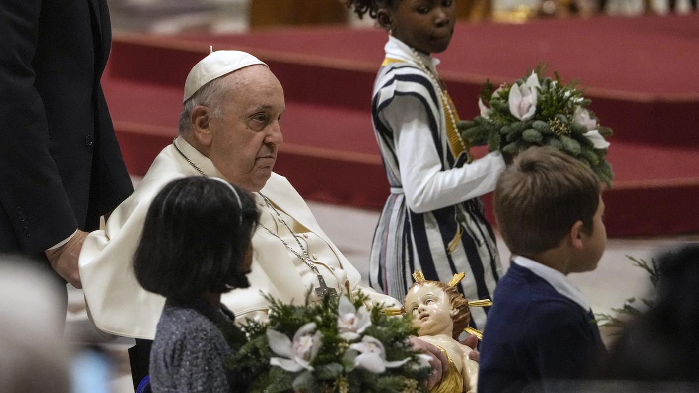 Papa Francesco porta la statua di Gesu bambino nel presepe di San Pietro dopo la messa di Mezzanotte