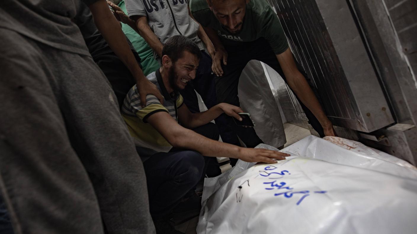 Palestinesi si riuniscono accanto ai corpi dei parenti uccisi venerdì in un campo nell'area di Al-Mawasi