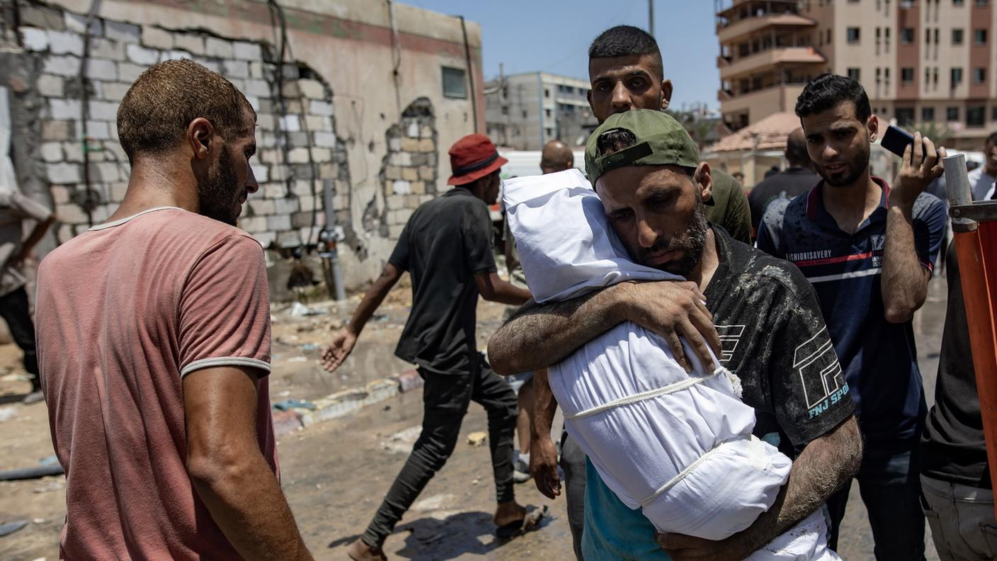 Un palestinese con il corpo del figlio, ucciso da un raid israeliano sul campo profughi di Al-Mawasi, nell'area di Khan Yunis (13 luglio 2024)