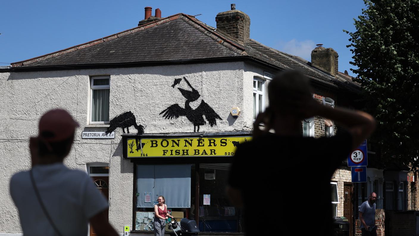 I due pellicani che mangiano pesci sull'insegna di un fish bar a Walthamstow