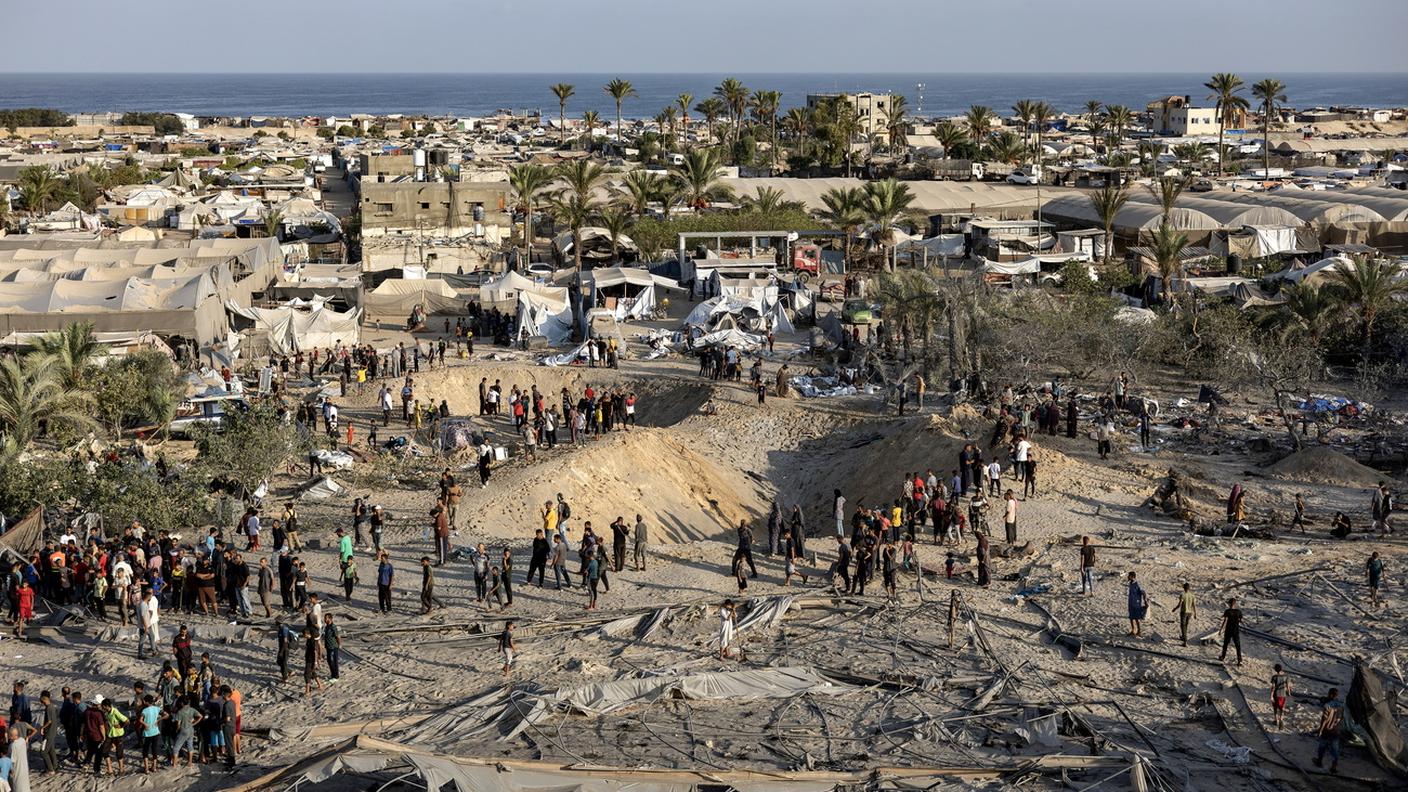 Palestinesi ispezionano i crateri mentre cercano i dispersi in seguito agli attacchi aerei israeliani sulla zona umanitaria di Al-Mawasi.