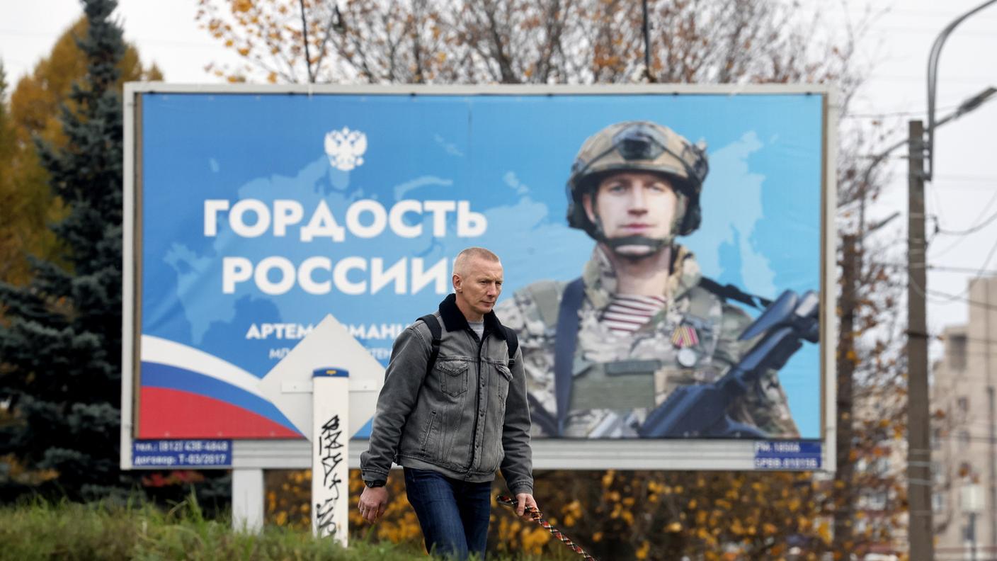 San Pietroburgo, ottobre 2024: un uomo passa davanti a un cartellone che raffigura un soldato russo e recita “Orgoglio della Russia”