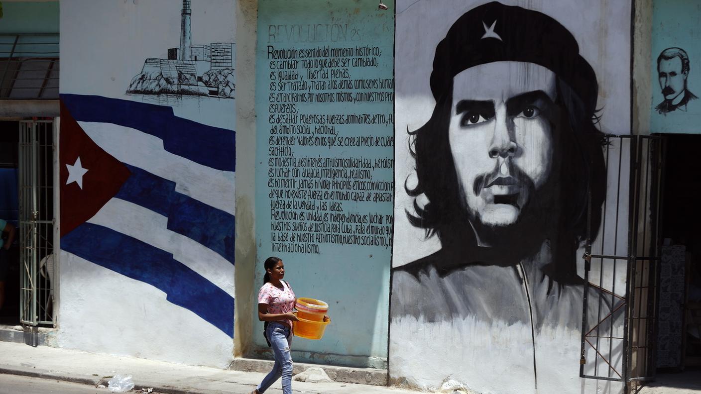 Una donna cammina di fronte a un murale con l'immagine del rivoluzionario Ernesto Che Guevara, L'Avana, Cuba