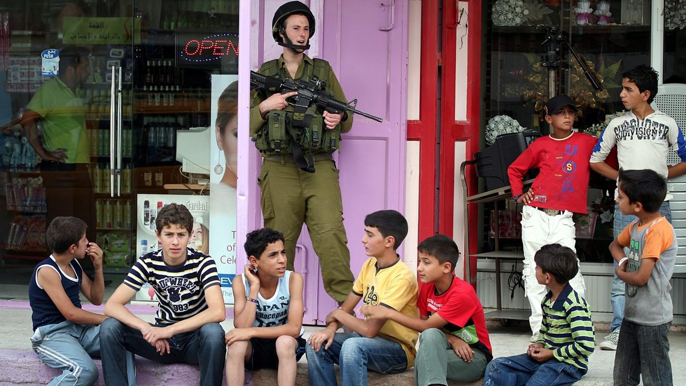 Un soldato israeliano tra giovani palestinesi