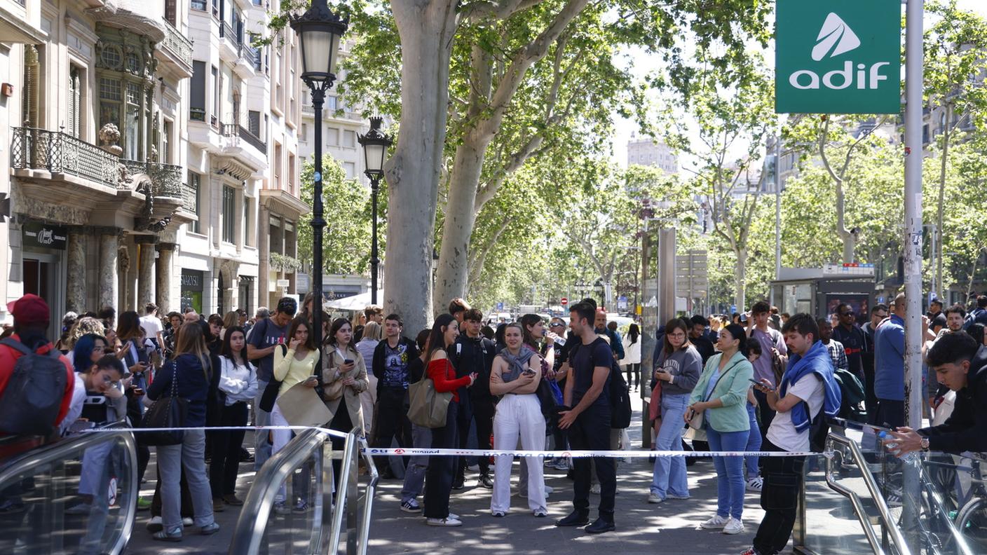 Pendolari attendono fuori dalla stazione ferroviaria di Sants durante il blackout che ha colpito Spagna e Portogallo 