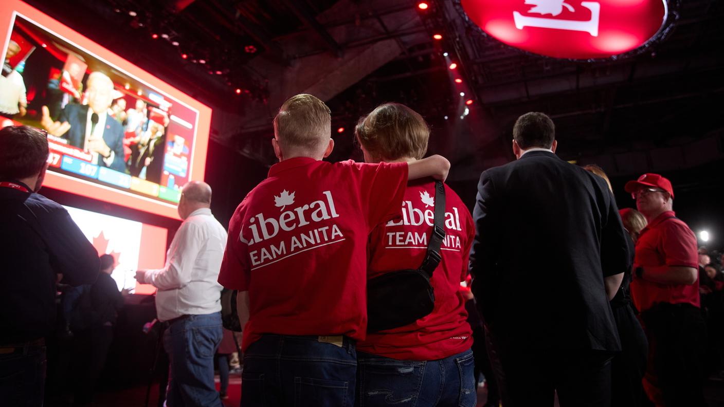 Sostenitori liberali canadesi ascoltano il premier Mark Carney su un maxischermo in una sede del partito a Ottawa
