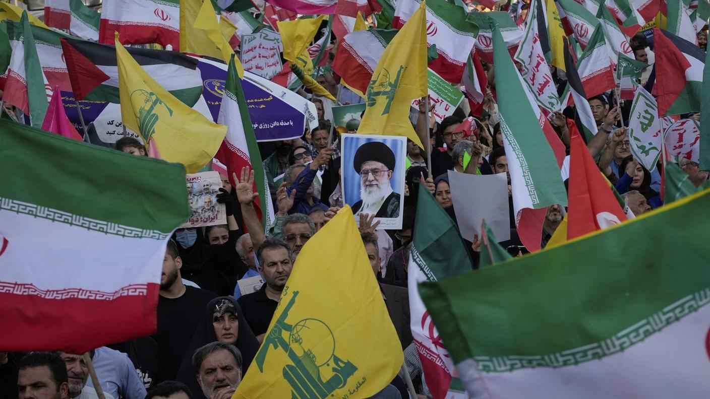 Dimostranti sventolano bandiere iraniane e di Hezbollah durante una manifestazione sciita