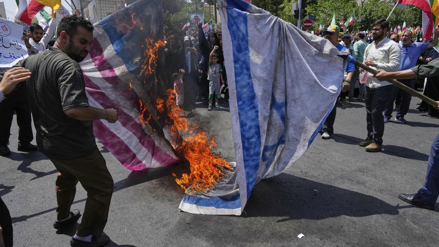 Una bandiera israeliana e una statunitense date alle fiamme a Teheran