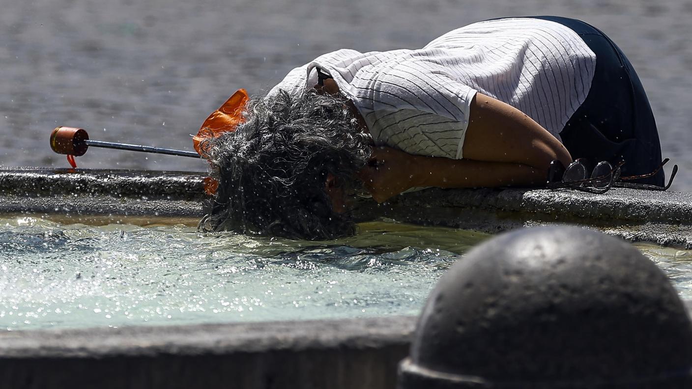 Una donna a Roma cerca un po' di refrigerio in una fontana