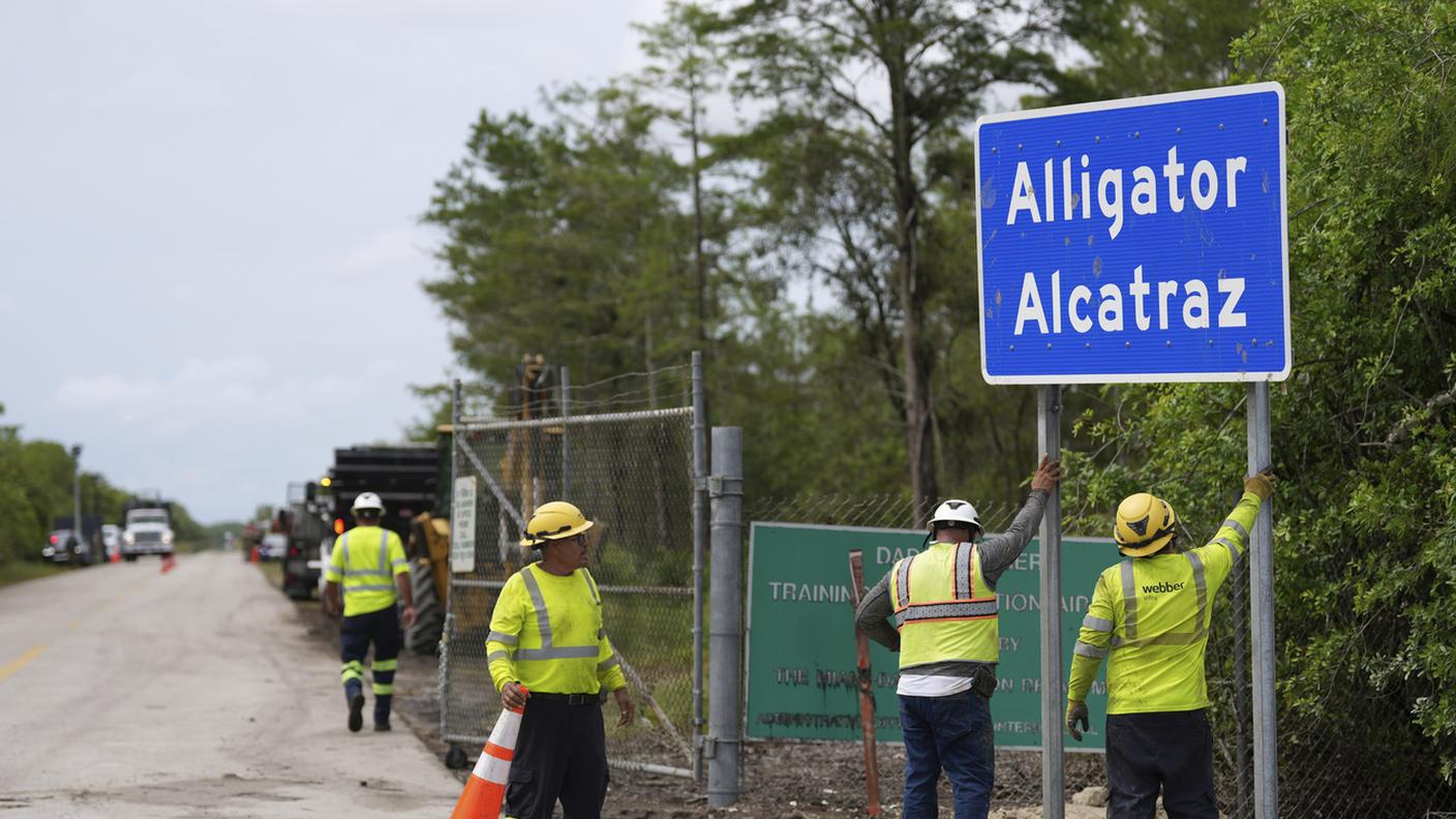 Operai installano il cartello nei pressi dell'entrata di "Alligator Alcatraz"