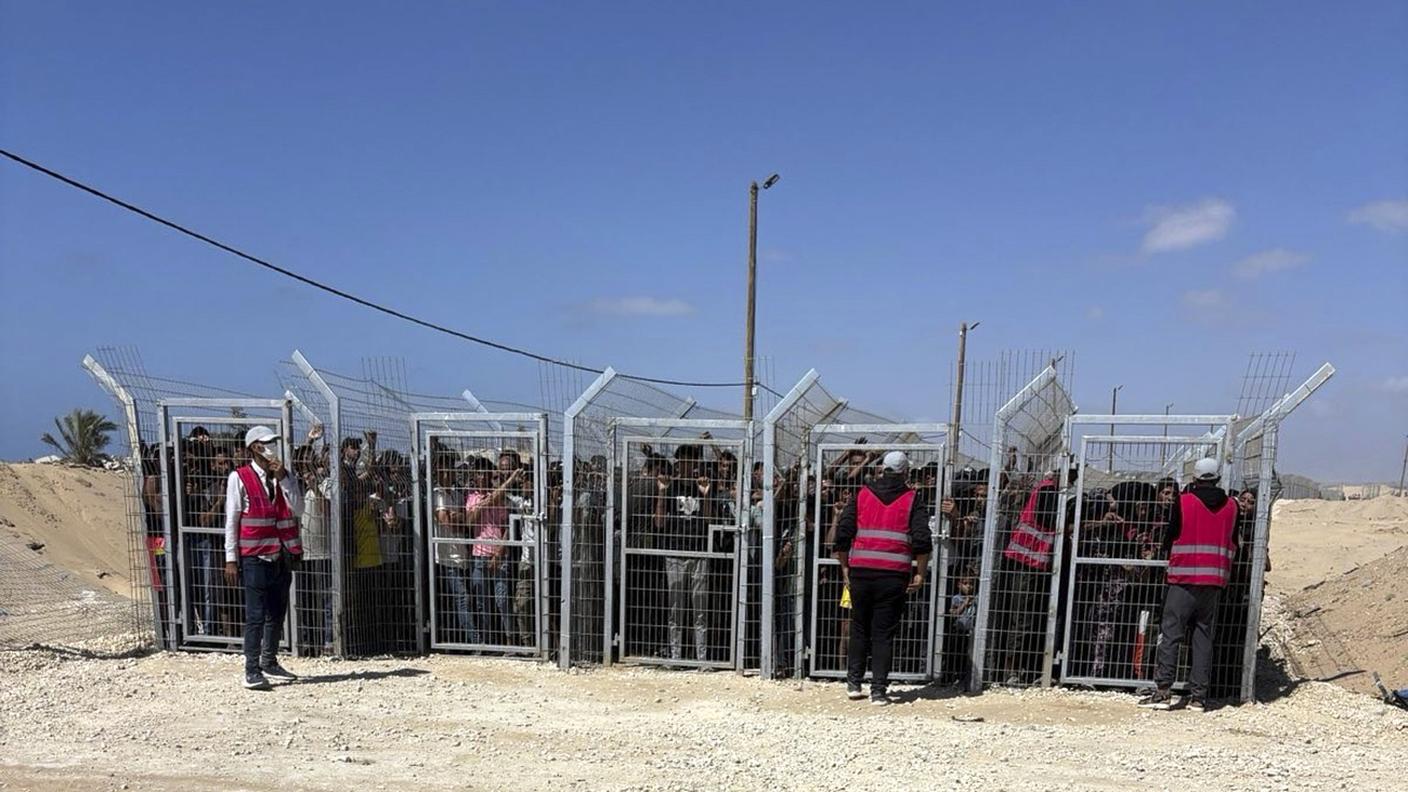 Palestinesi dietro i cancelli davanti a un sito di GHF per la distribuzione di aiuti nella Striscia di Gaza