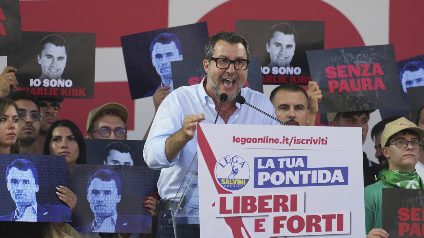 Matteo Salvini parla dal palco di Pontida domenica con alle spalle vari ritratti di Charlie Kirk