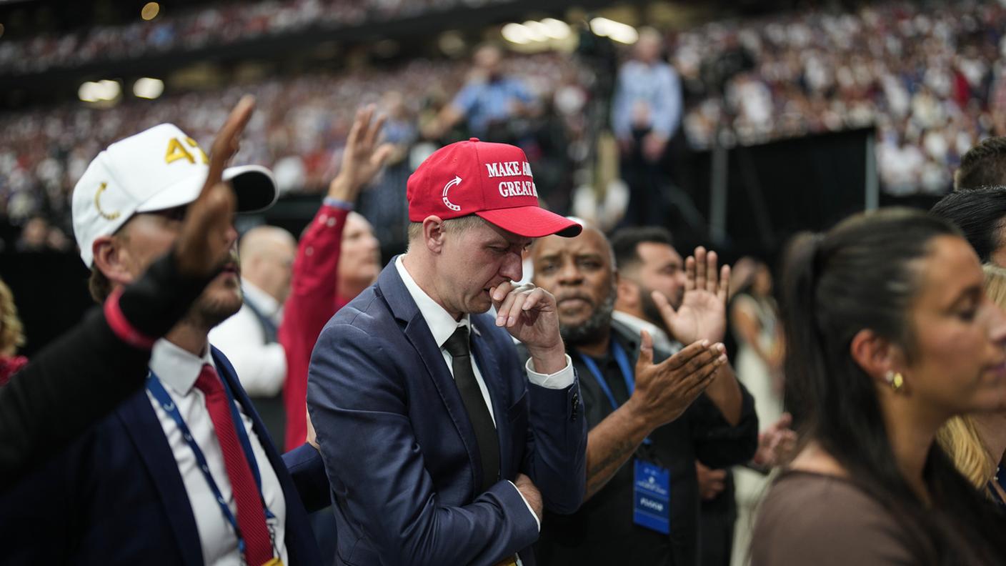Un uomo con il cappellino rosso con lo slogan di Trump si emoziona al funerale di Charlie Kirk allo State Farm Stadium