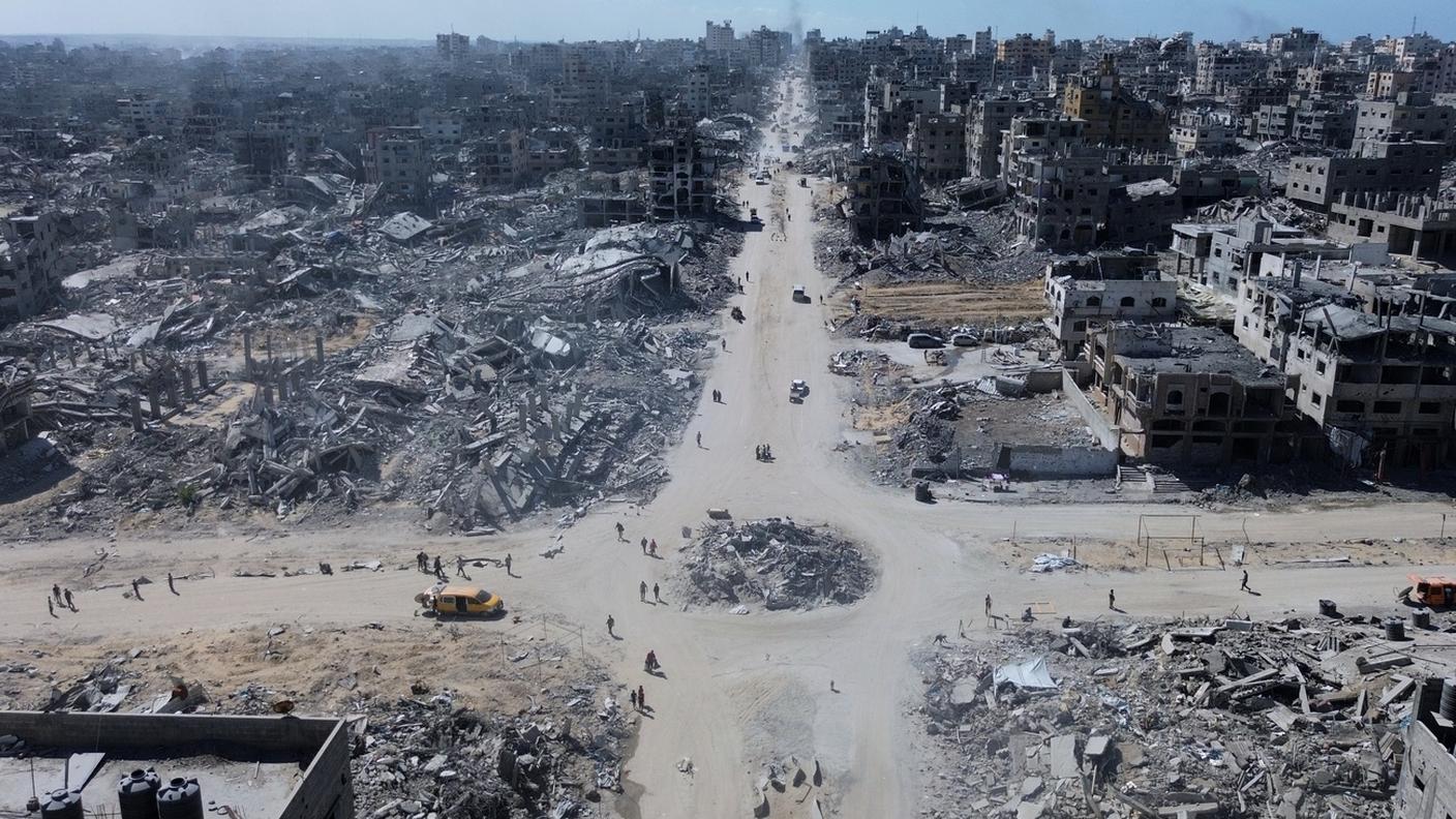 Palestinesi camminano in un incrocio circondato da edifici distrutti durante due anni di bombardamenti dell'esercito israeliano nella città di Gaza, mercoledì 15 ottobre 2025