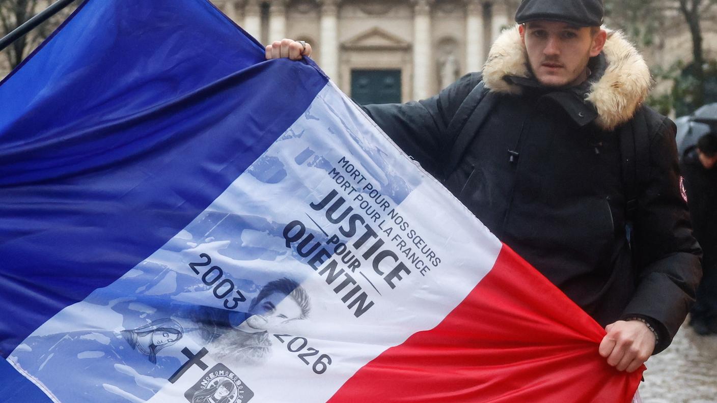 Un giovane regge una bandiera francese con un omaggio a Quentin Deranque
