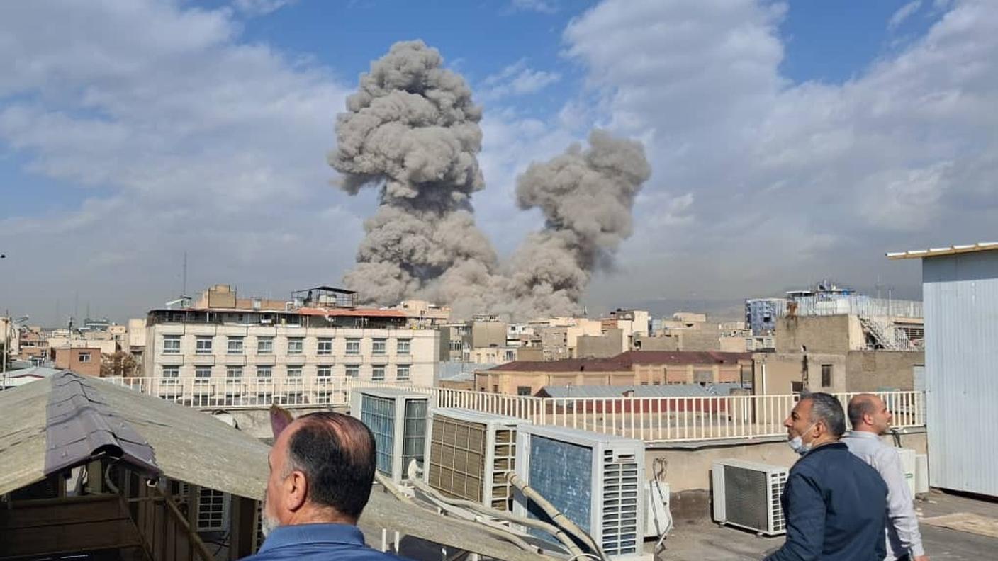 Tre persone osservano gli attacchi su Teheran da un tetto