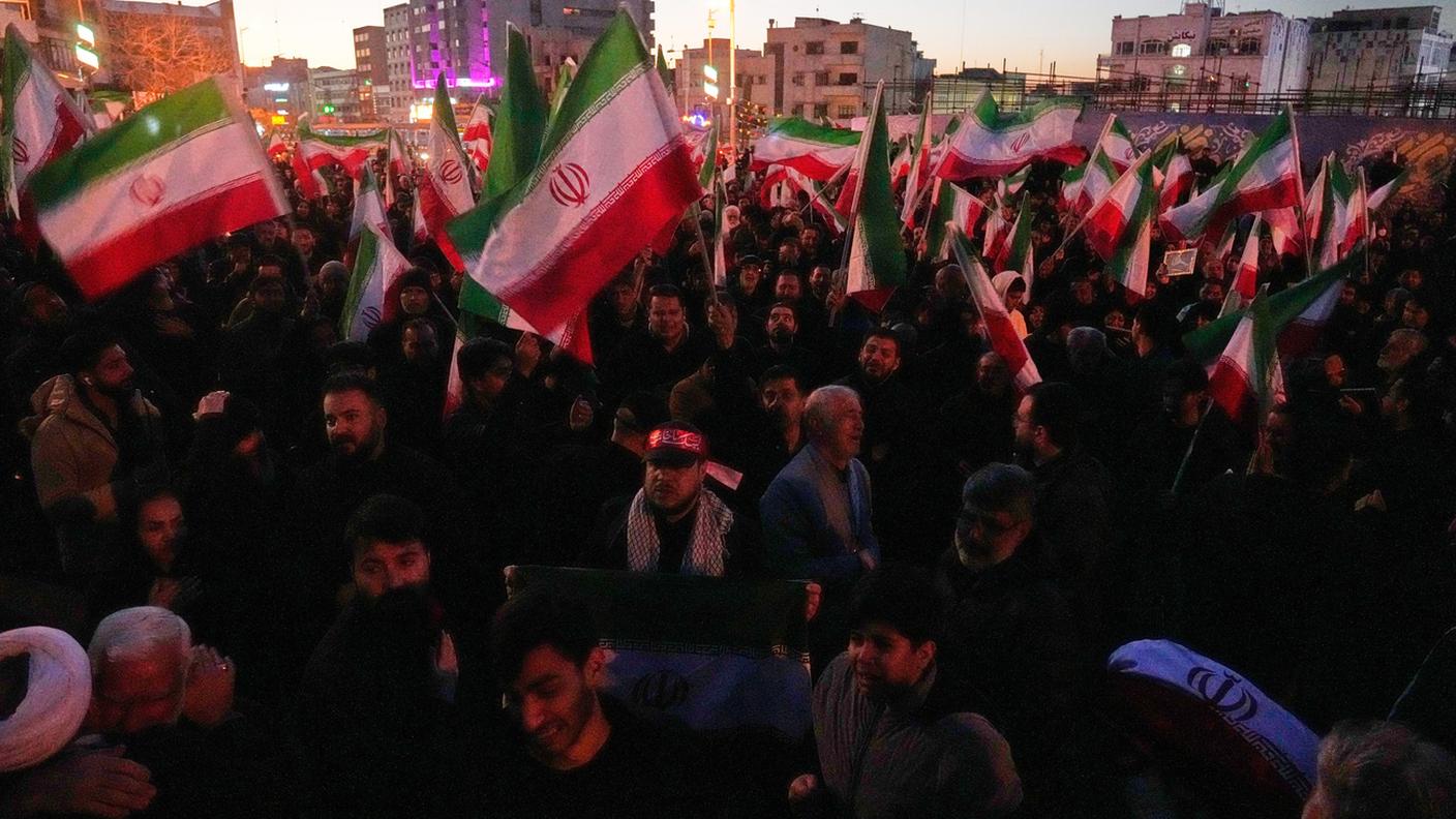 Una folla sventola bandiere iraniane durante una cerimonia di lutto, dopo che la TV di Stato iraniana annuncia la morte della Guida Suprema Ali Khamenei. Teheran, 1° marzo 2026.