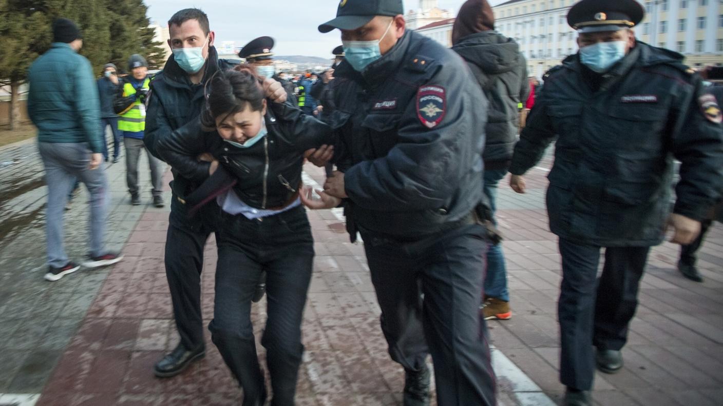 Una donna fermata dagli agenti durante una dimostrazione a favore di Navalny in una località della Russia orientale