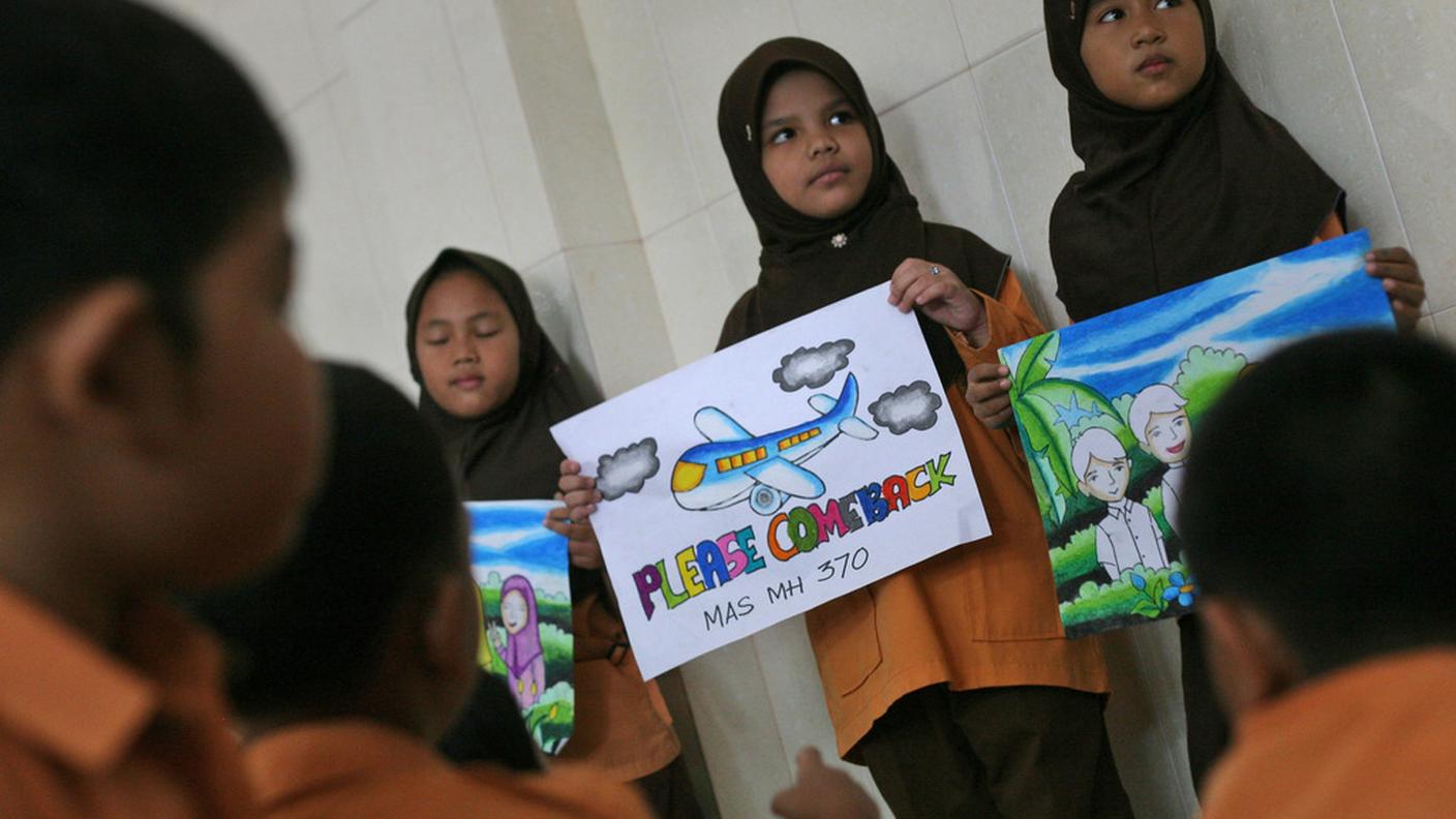 Tre ragazze espongono cartelli di sostegno ai passeggeri del volo MH370