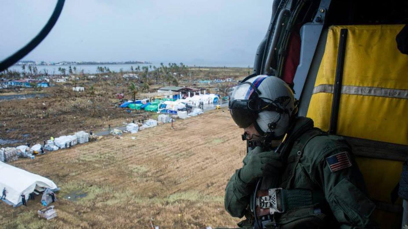 Un militare statunitense a bordo di un elicottero prossimo all'atterraggio su una delle isole devastate