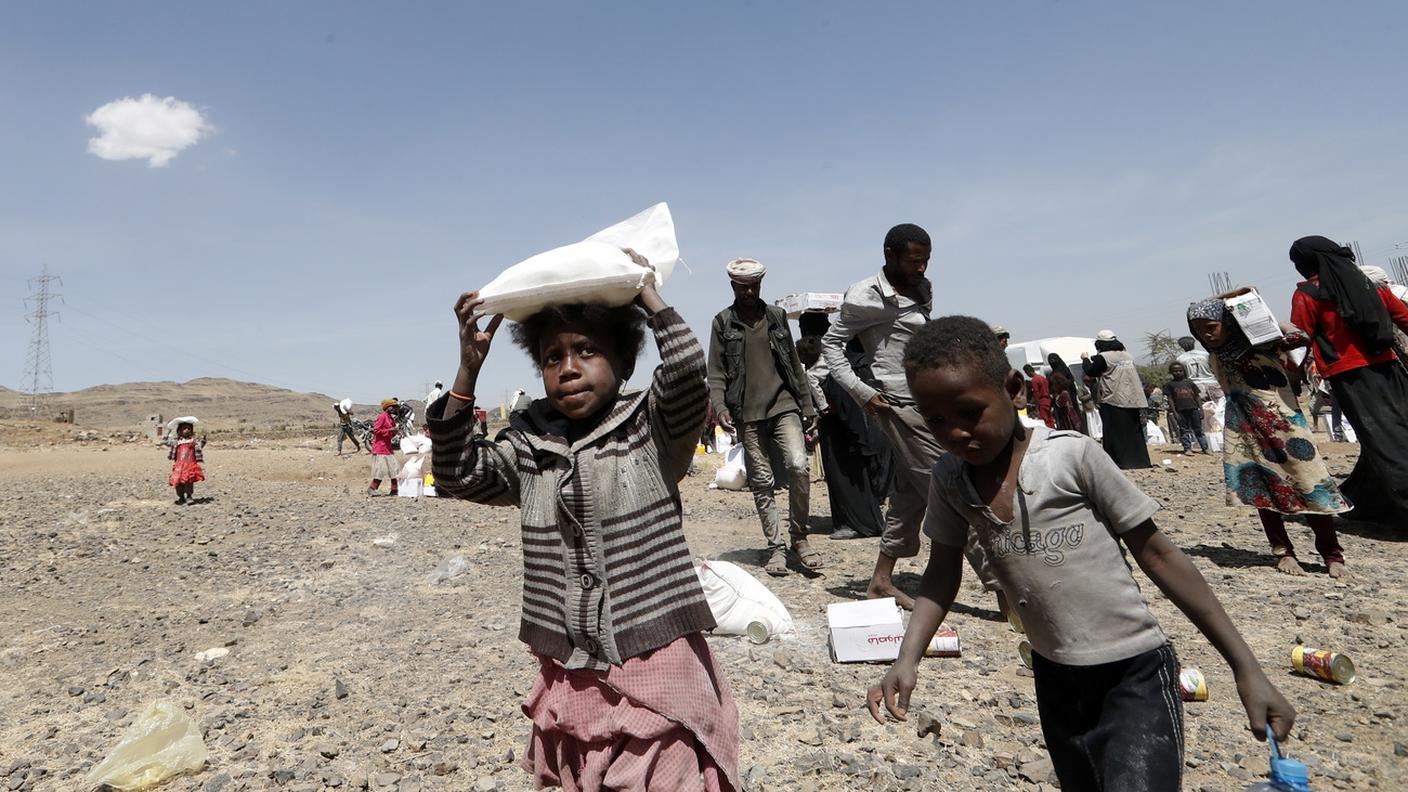 Bambini e adulti in un campo profughi in Yemen ricevono gli aiuti umanitari che per un po' garantiranno loro la sopravvivenza