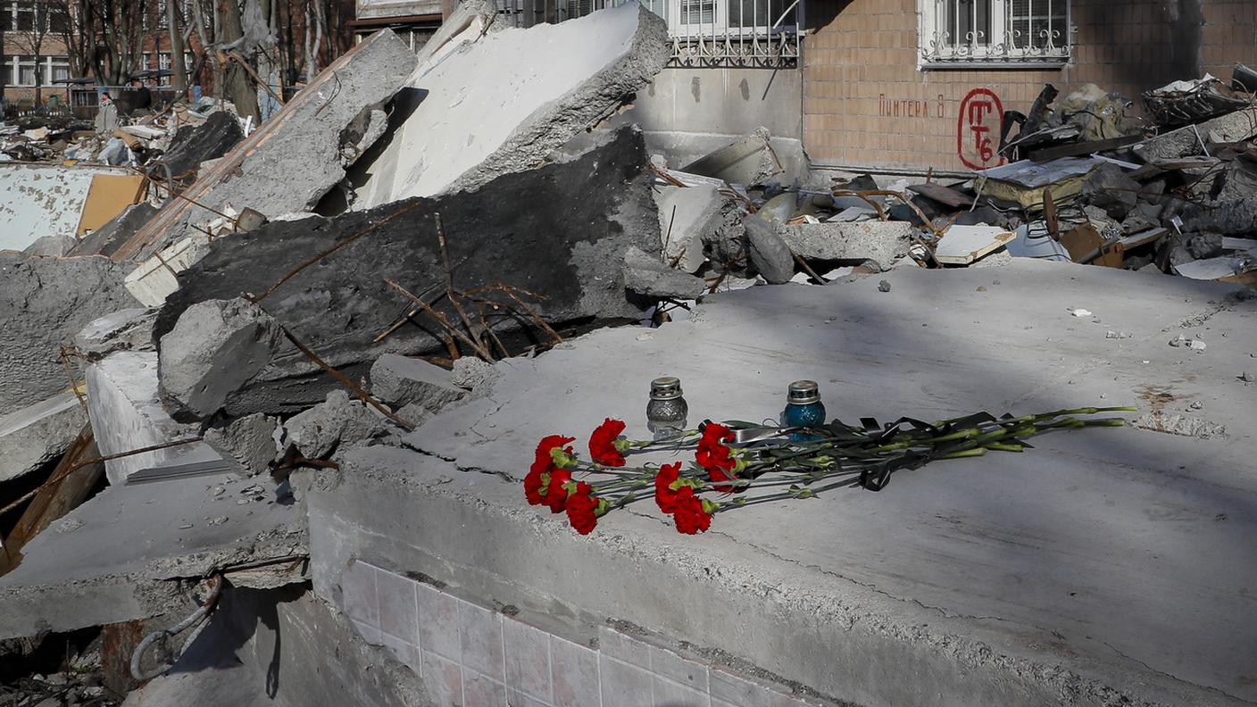 Fiori e candele in ricordo degli abitanti di un palazzo raso al suolo dai russi a Donetsk, Donbass