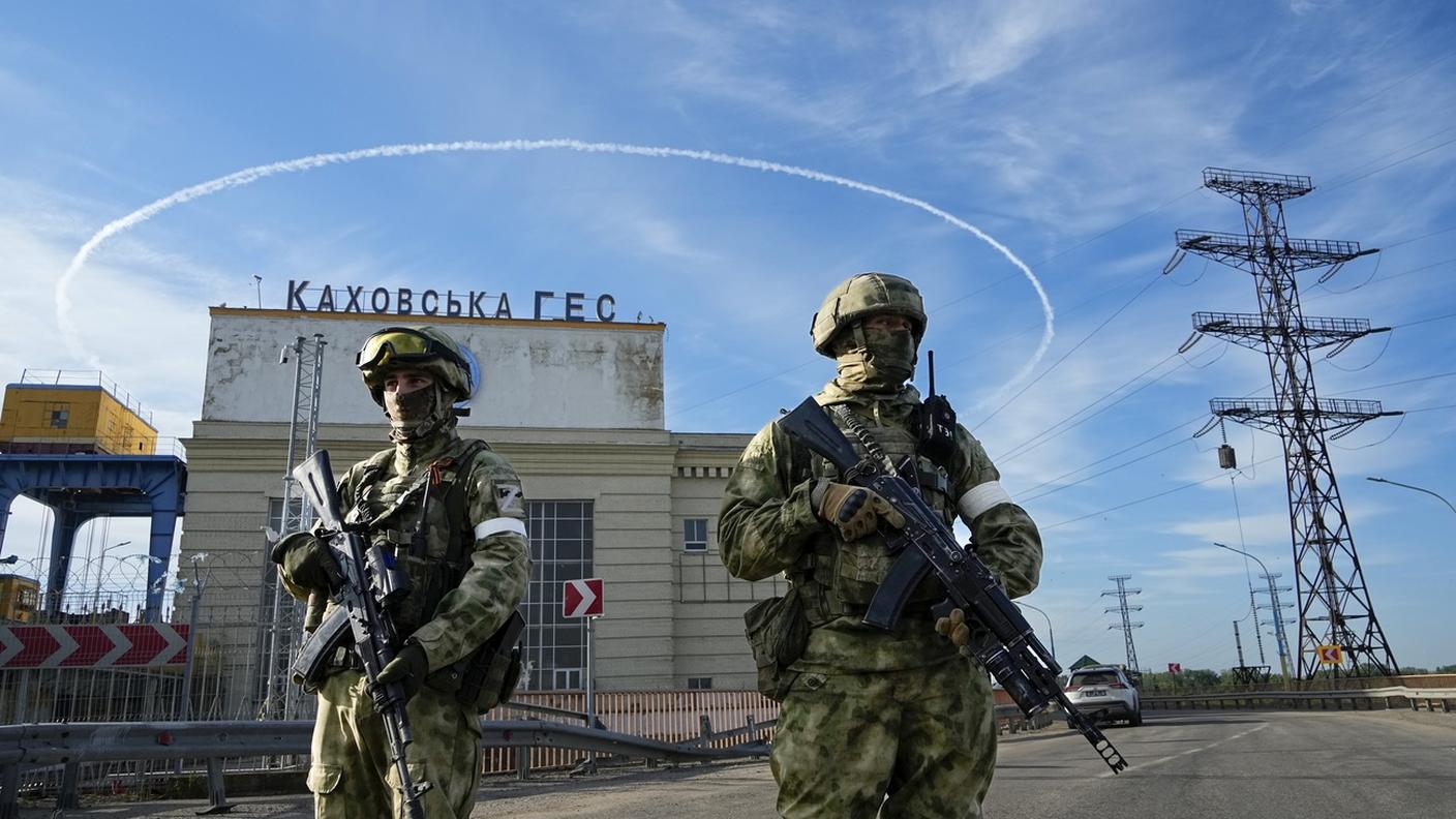 Soldati russi presidiano l'ingresso di una centrale idroelettrica nella regione di Cherson