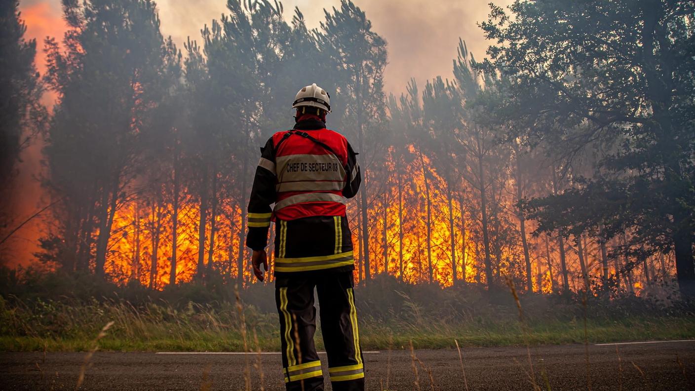 Un pompiere francese di fronte alla foresta in fiamme a Landiras, nella Gironda