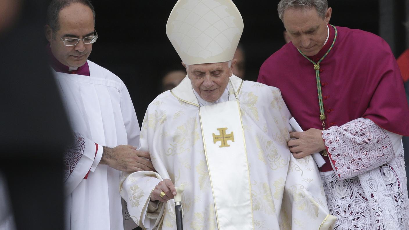 L'arrivo del Papa emerito, sostenuto da un bastone e dall'ar