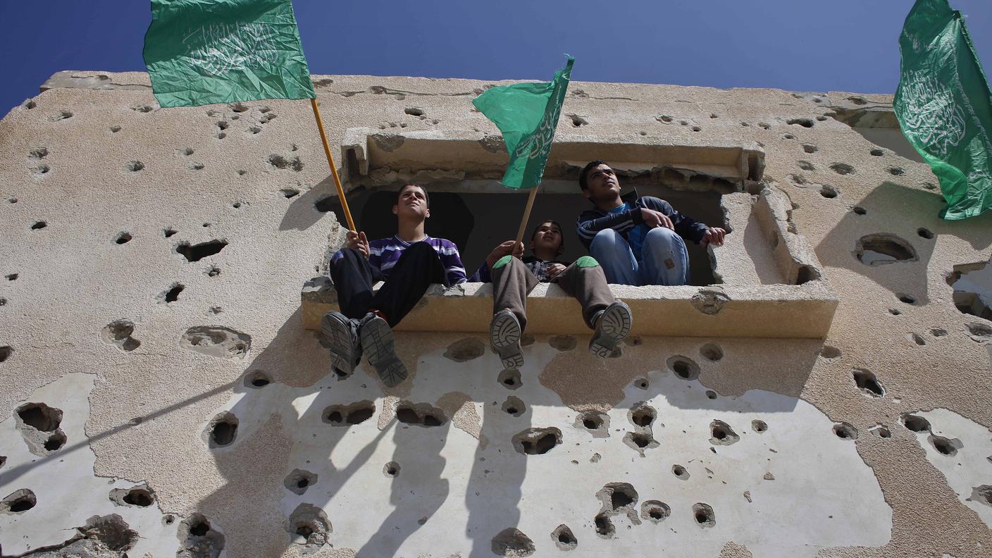 Ragazzi palestinesi stanno sventolando le bandiere di Hamas durante una manifestazione per chiedere alle autorità egiziane di aprire le frontiere di Rafah, al confine fra la striscia di Gaza e l'Egitto