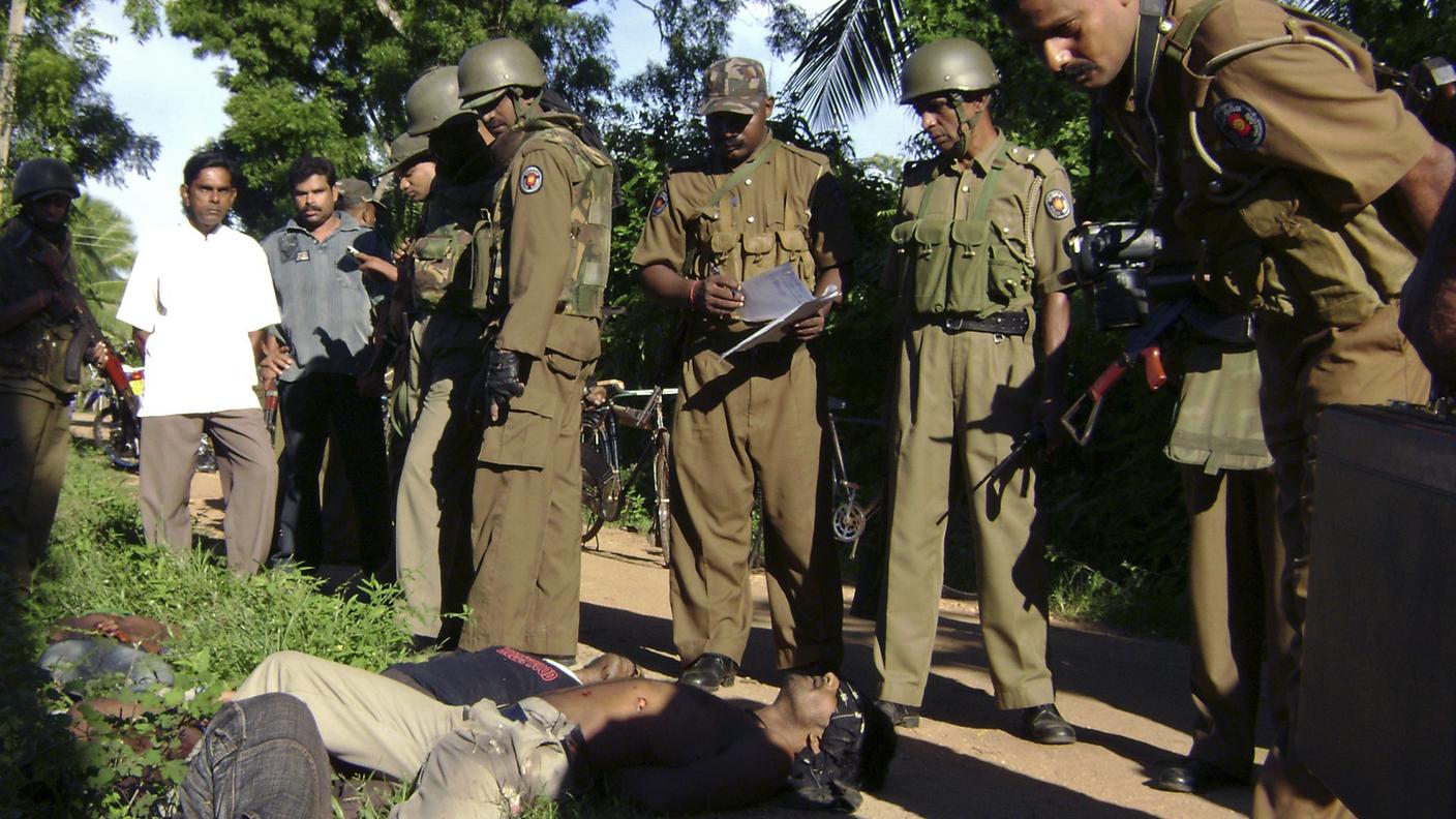 Ufficiali della polizia dello Sri Lanka guardano i corpi di civili appartenenti alla minoranza etnica Tami che presentano chiari segni di tortura