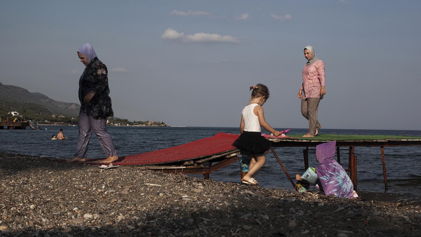 Alcune donne turche con il costume da bagno coperto (cosiddetto burqini) stanno tornando allaspiaggia dopo una nuotata. Assos / Ayvacık / Çanakkale, Turchia occidentale, il 12 agosto 2016