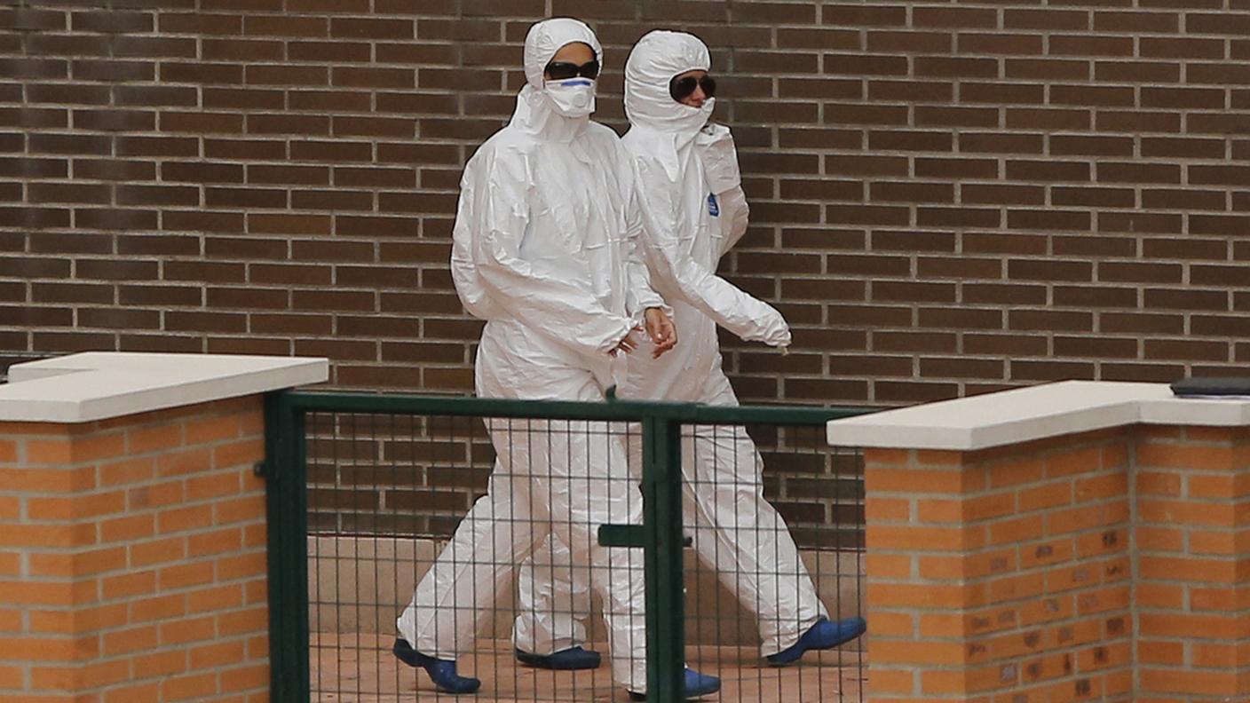 Medici con tute protettive, all'esterno della casa dell'infermiera contagiata 