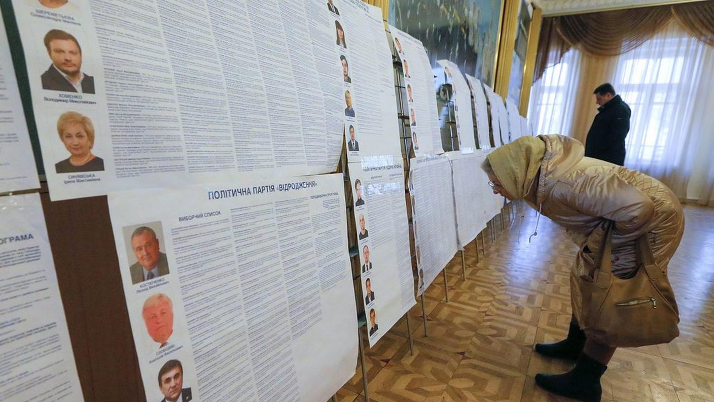 Un'elettrice di Kiev cerca di orientarsi fra le varie liste in lizza